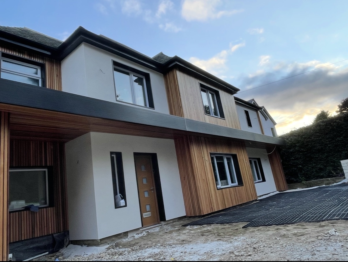 A house finished in cedar cladding and white K-Rend render at sunset.